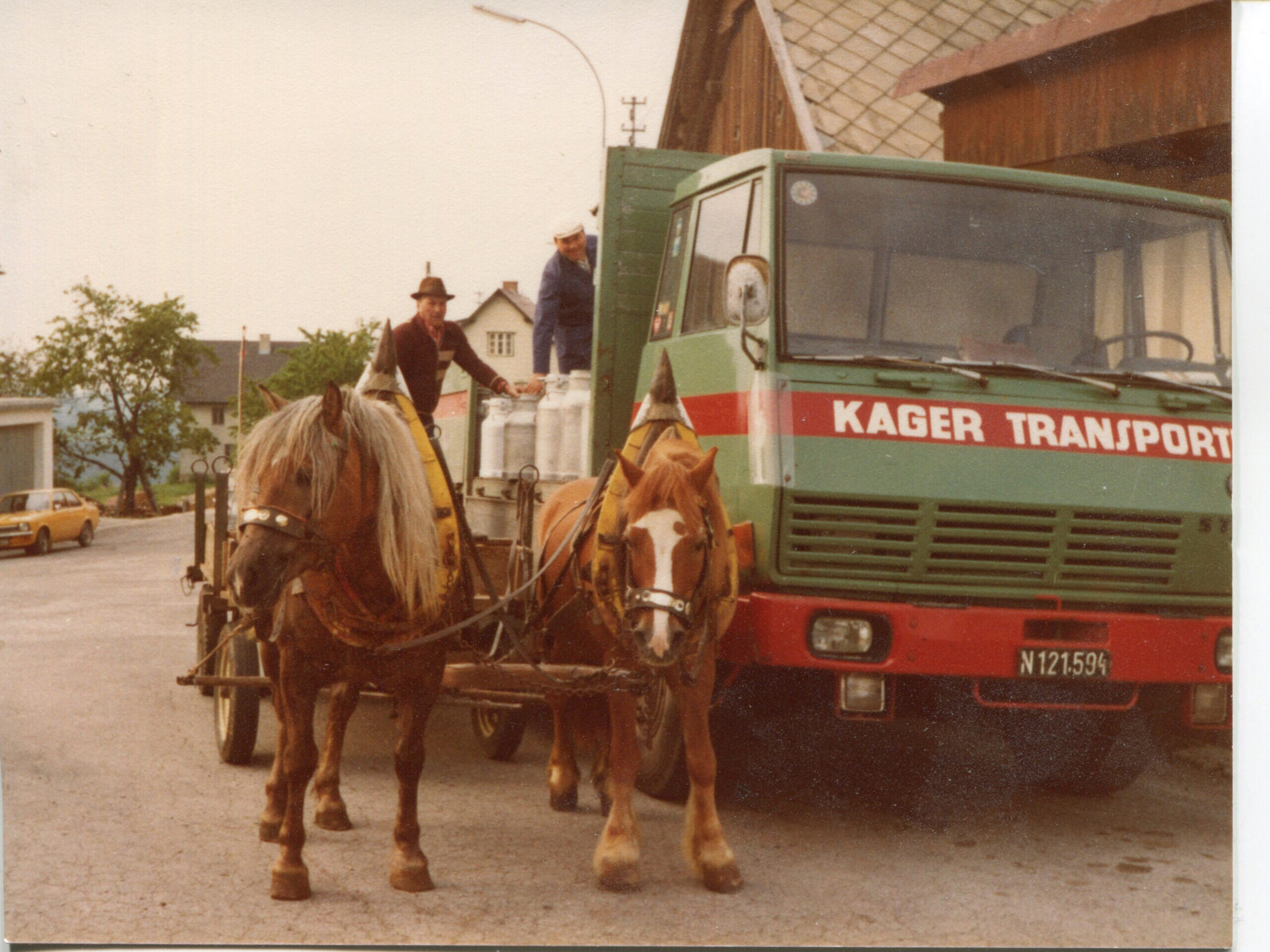 Ein grüner Lkw mit Milch steht neben einem Pferdefuhrwerk. 