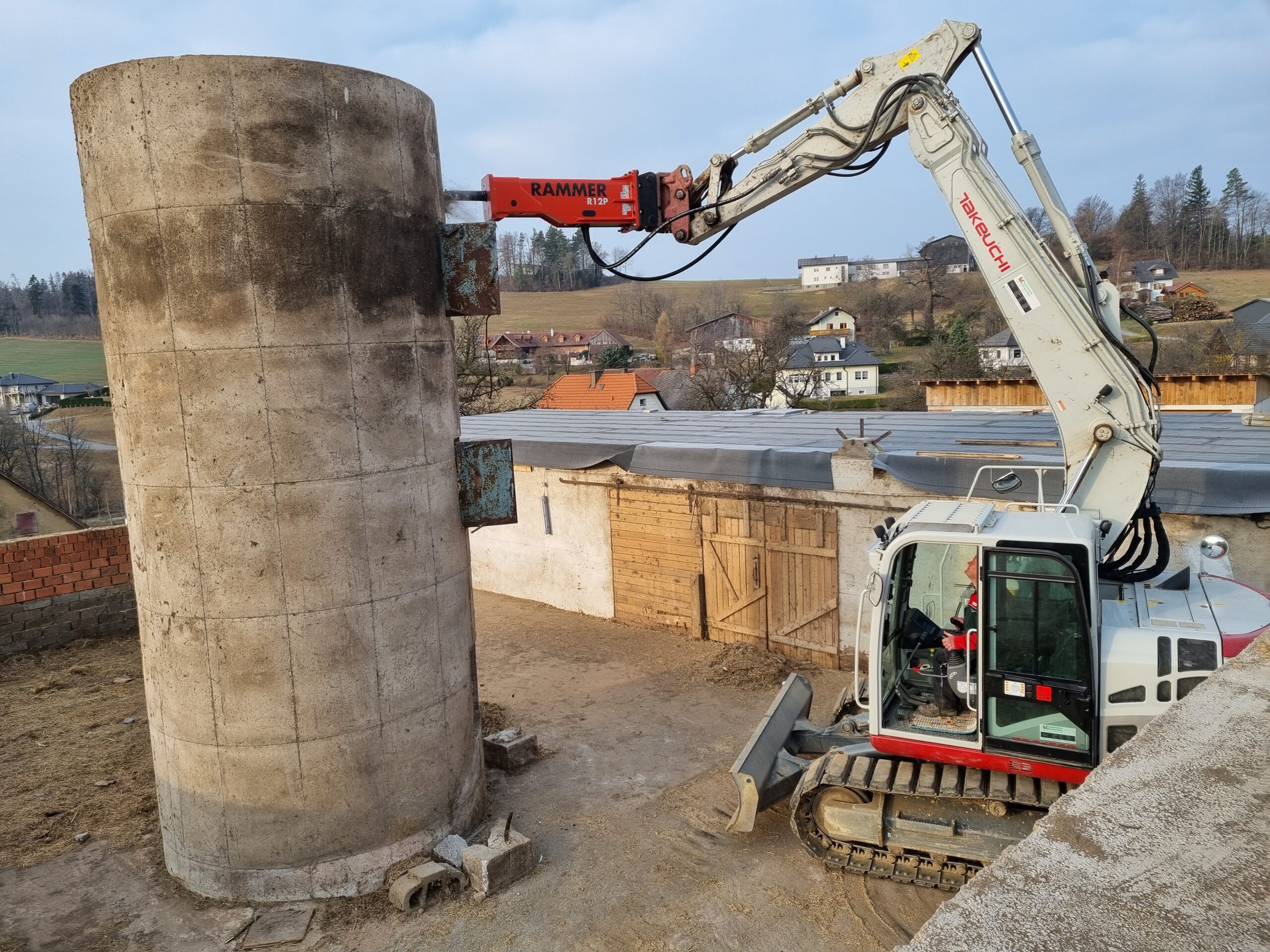 Ein Spezialbagger mit Presslufthammer bricht einen Betonsilo ab.