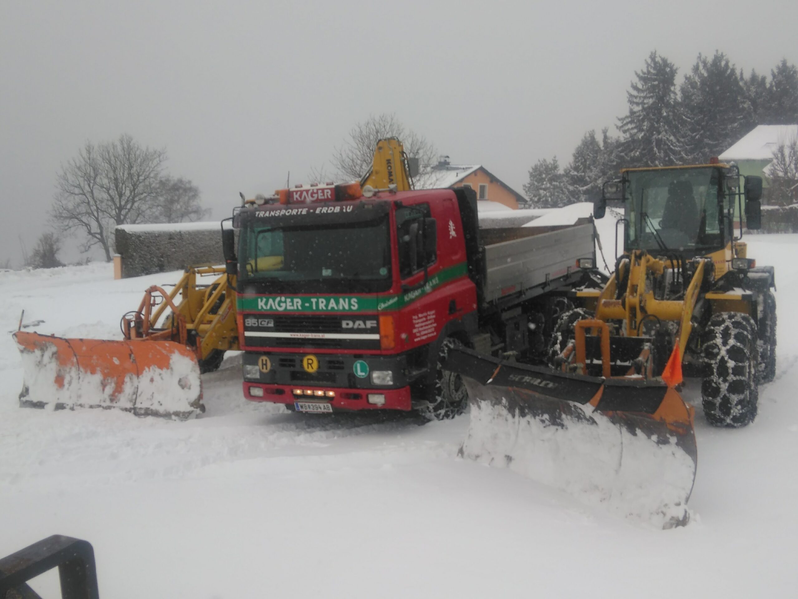 DAF-Kipper mit Schneepflug zwischen zwei Räumfahrzeugen im Schneefall.