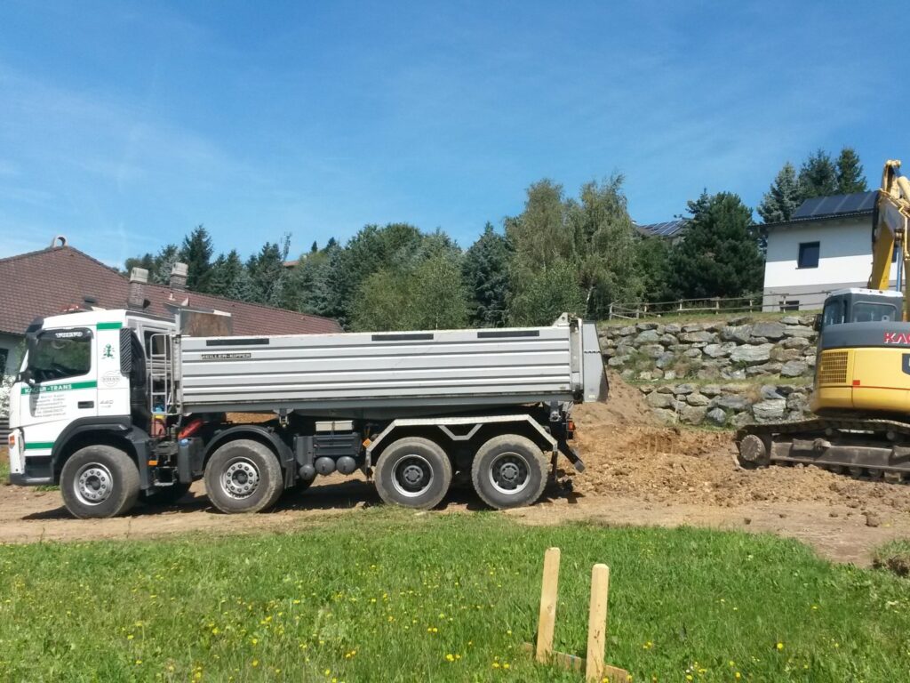 Kipper und Komatsu-Bagger beim Aushub auf Grundstück in Wohnsiedlung